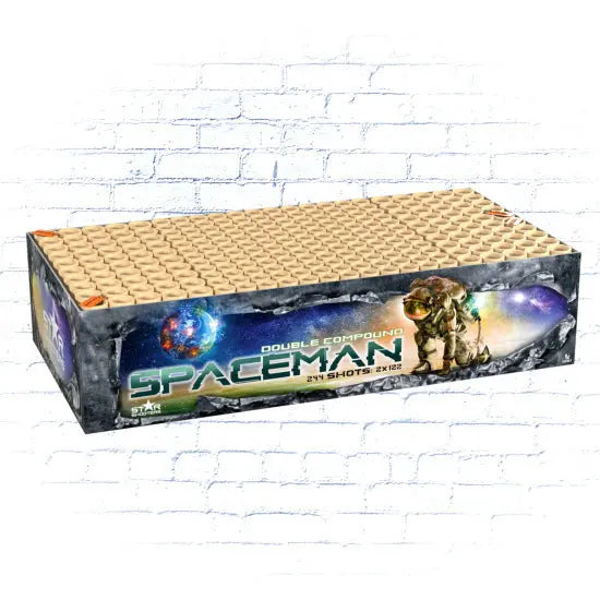 Eine rechteckige Lesli Spaceman Feuerwerksdose von Lesli mit Astronauten-, Planeten- und Sternenmotiven auf der Verpackung und einem Gittermuster auf der Oberseite vor einem weißen Backsteinhintergrund. Dies ist ein XXL Doppel-Verbundfeuerwerk.
